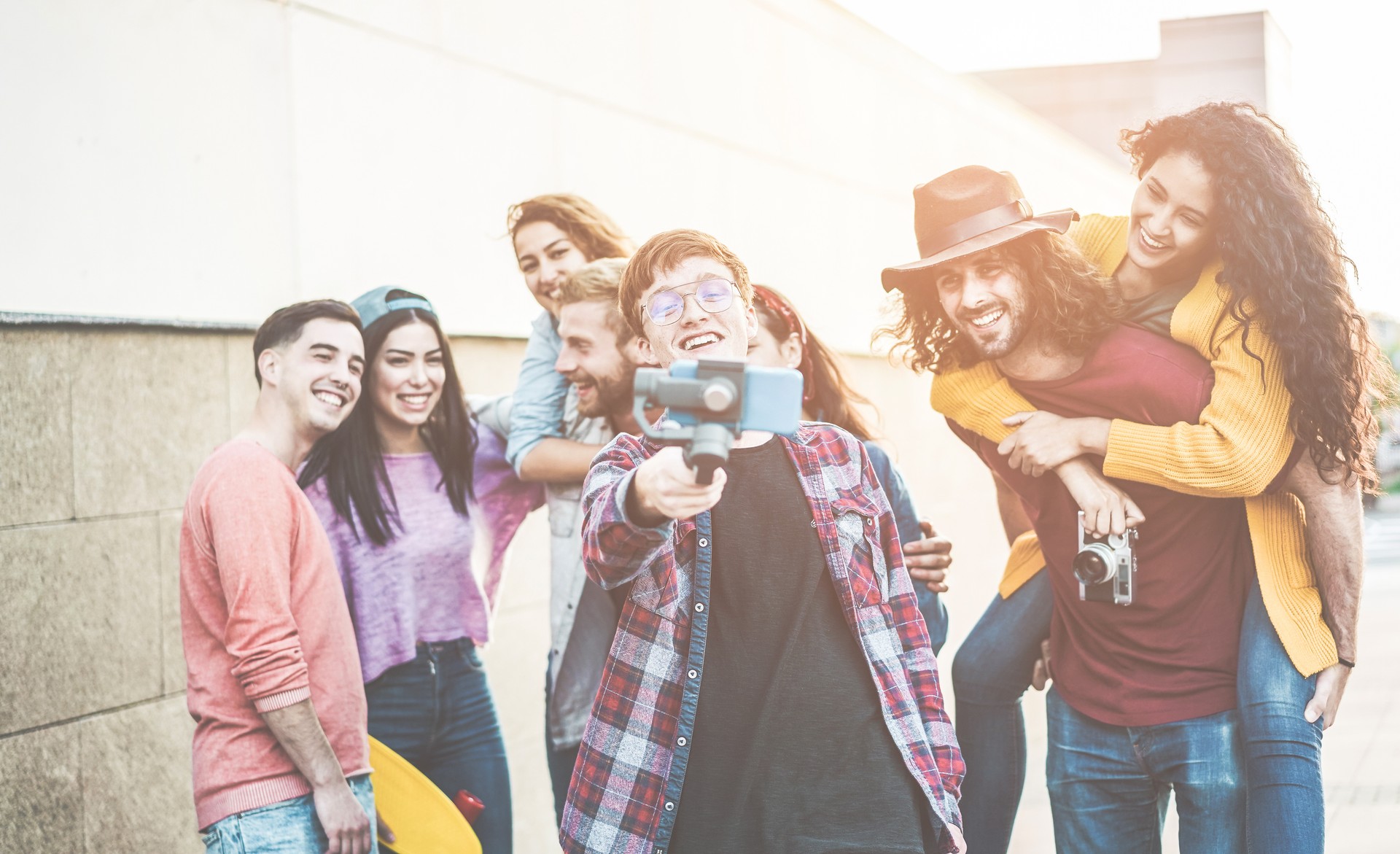 Happy millennial friends making video with smartphone gimbal outdoor - Young people having fun with new technology trends - Youth, tech lifestyle and social media concept - Focus on close-up guy face